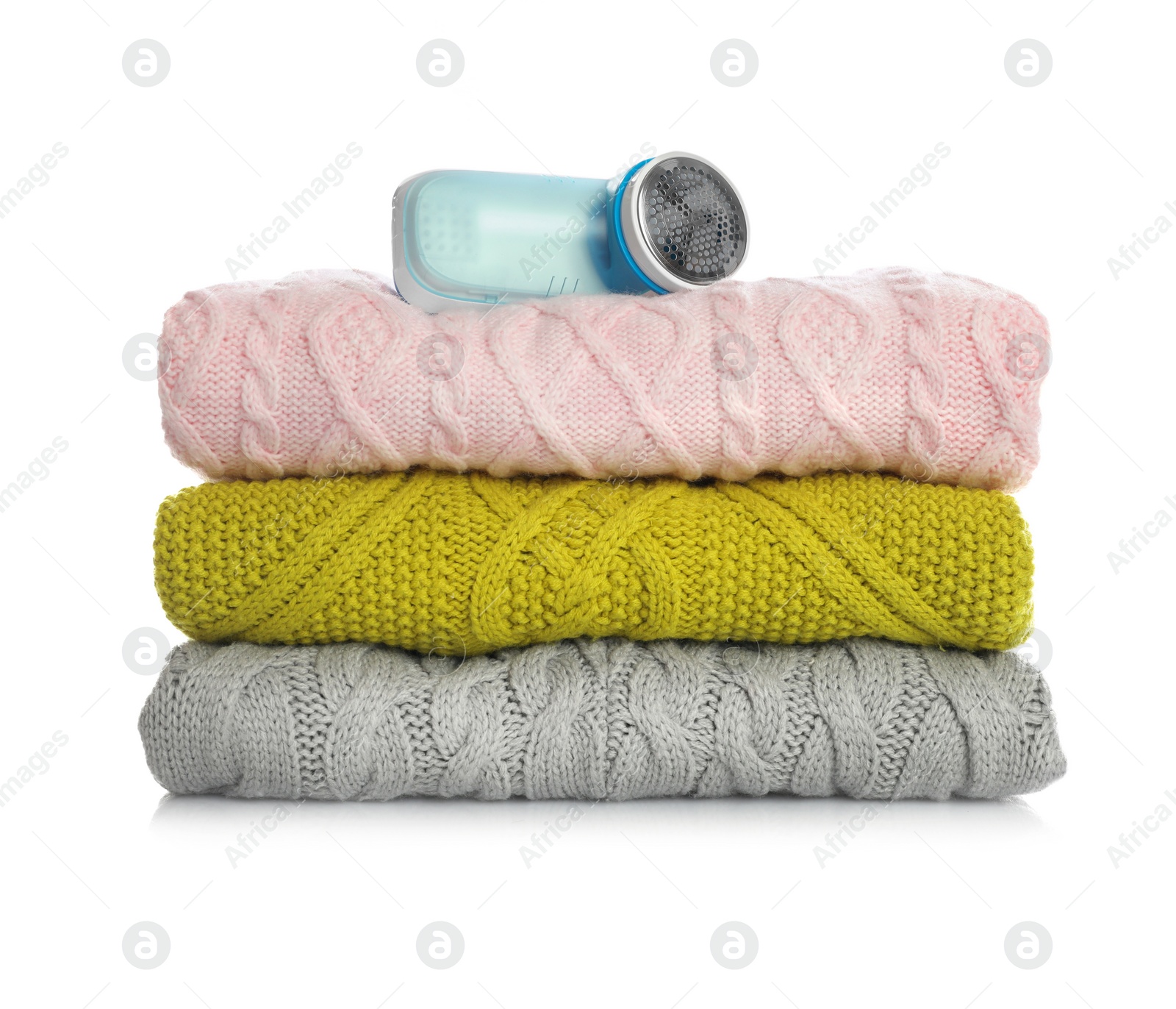 Photo of Modern fabric shaver and woolen clothes on white background