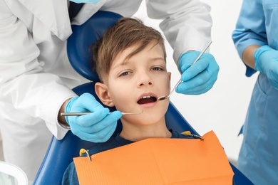 Professional dentist and assistant working with little boy in clinic