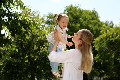 Happy mother with her daughter spending time together in park. Space for text