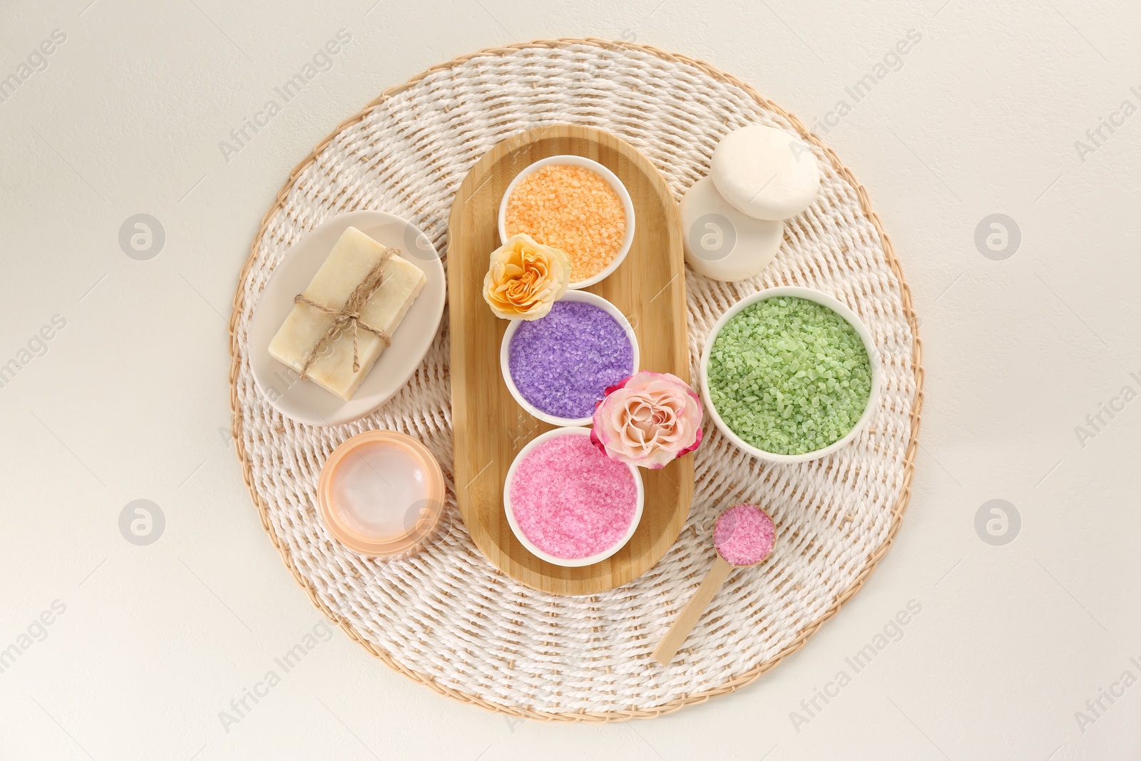 Photo of Bowls with sea salt, soap bars, jar of cream and roses on light table, flat lay
