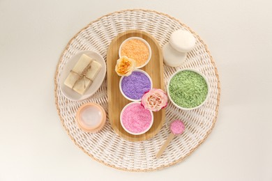 Bowls with sea salt, soap bars, jar of cream and roses on light table, flat lay