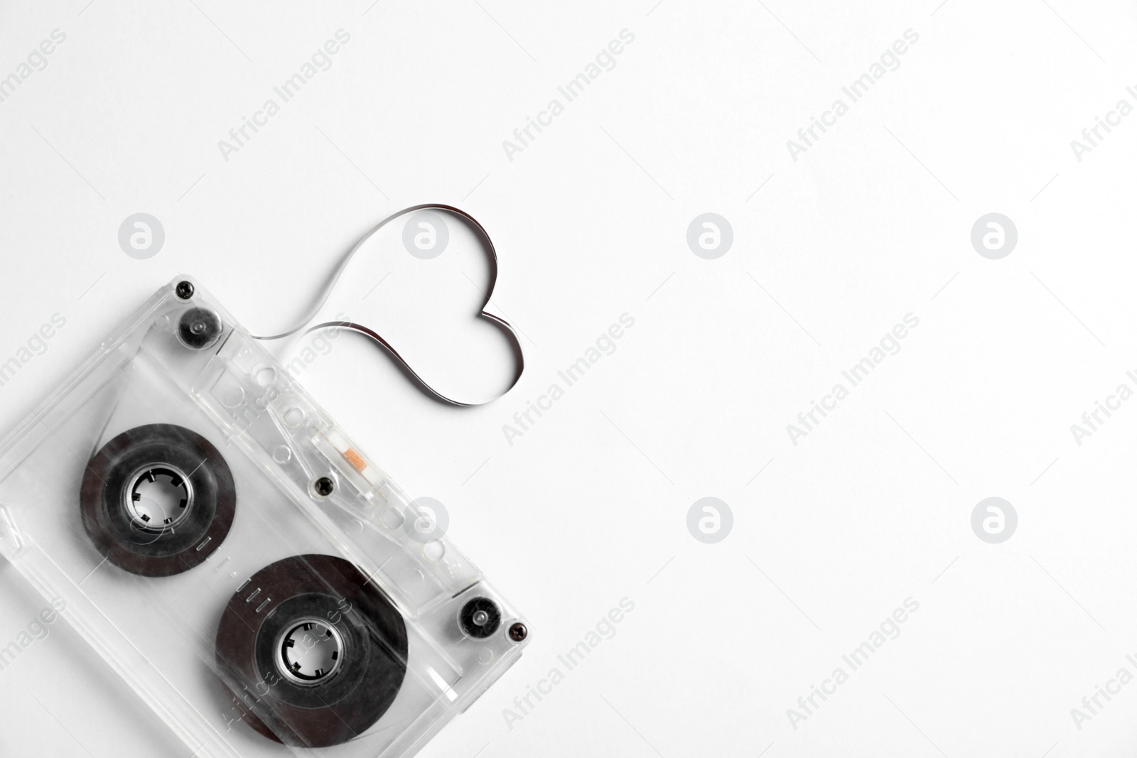 Photo of Music cassette and heart made with tape on white background, top view. Listening love song