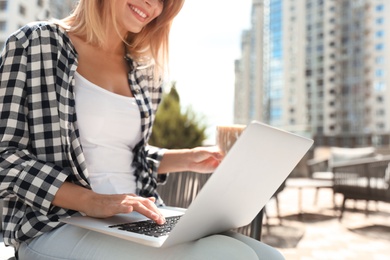 Photo of Woman using laptop at outdoor cafe, closeup