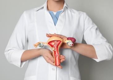 Photo of Doctor demonstrating model of female reproductive system on light grey background, closeup. Gynecological care