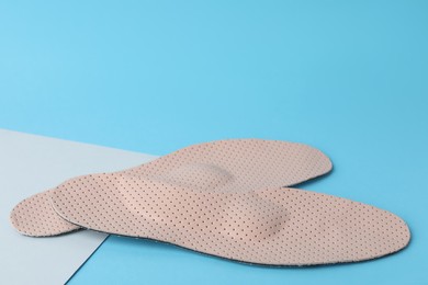 Photo of Beige comfortable orthopedic insoles on light blue background