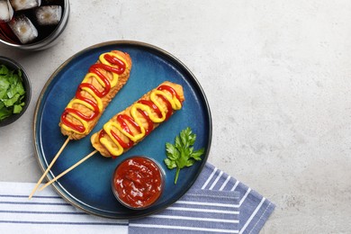 Photo of Delicious corn dogs with mustard and ketchup served on light table, flat lay