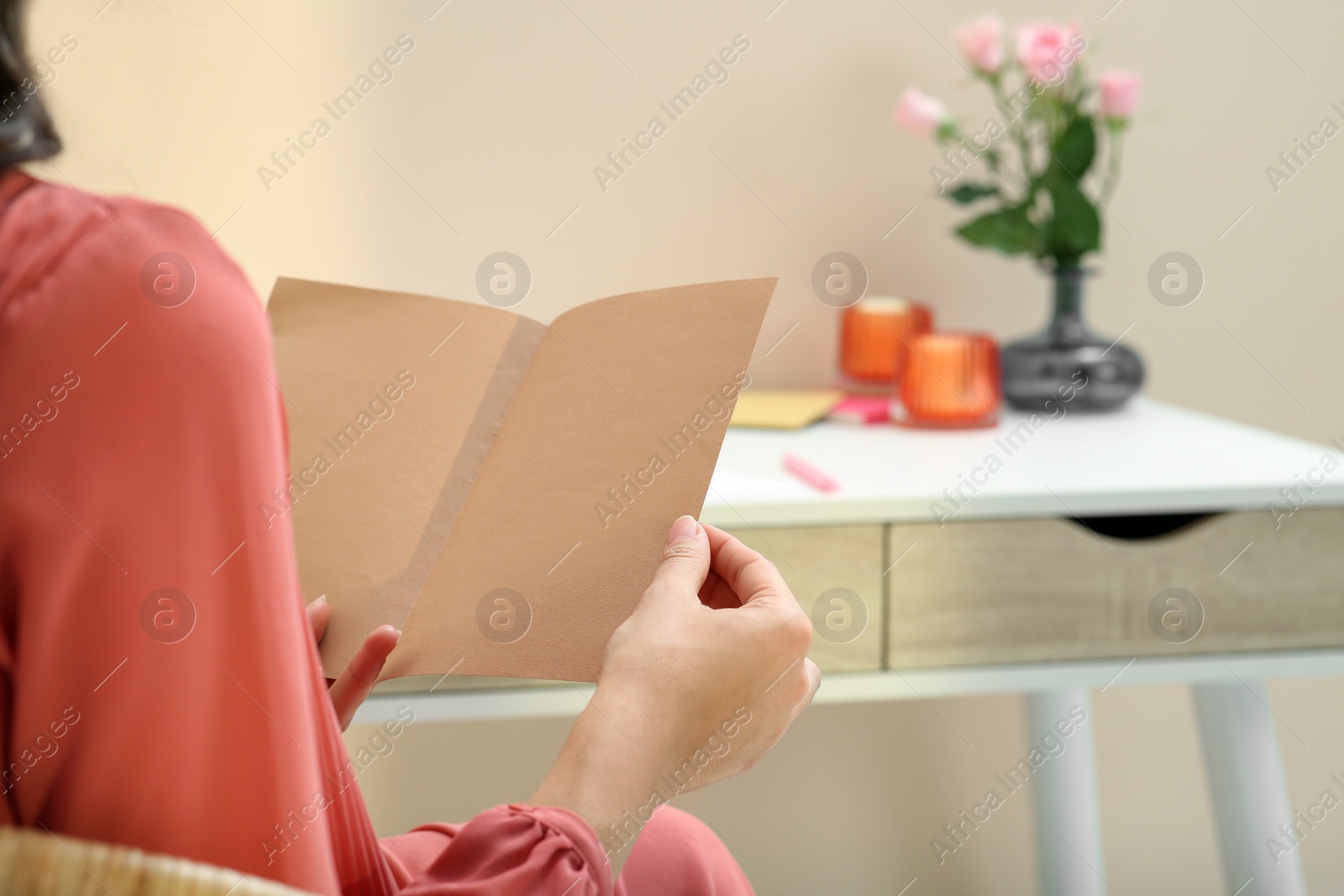 Photo of Young woman with greeting card in living room, closeup. Space for text