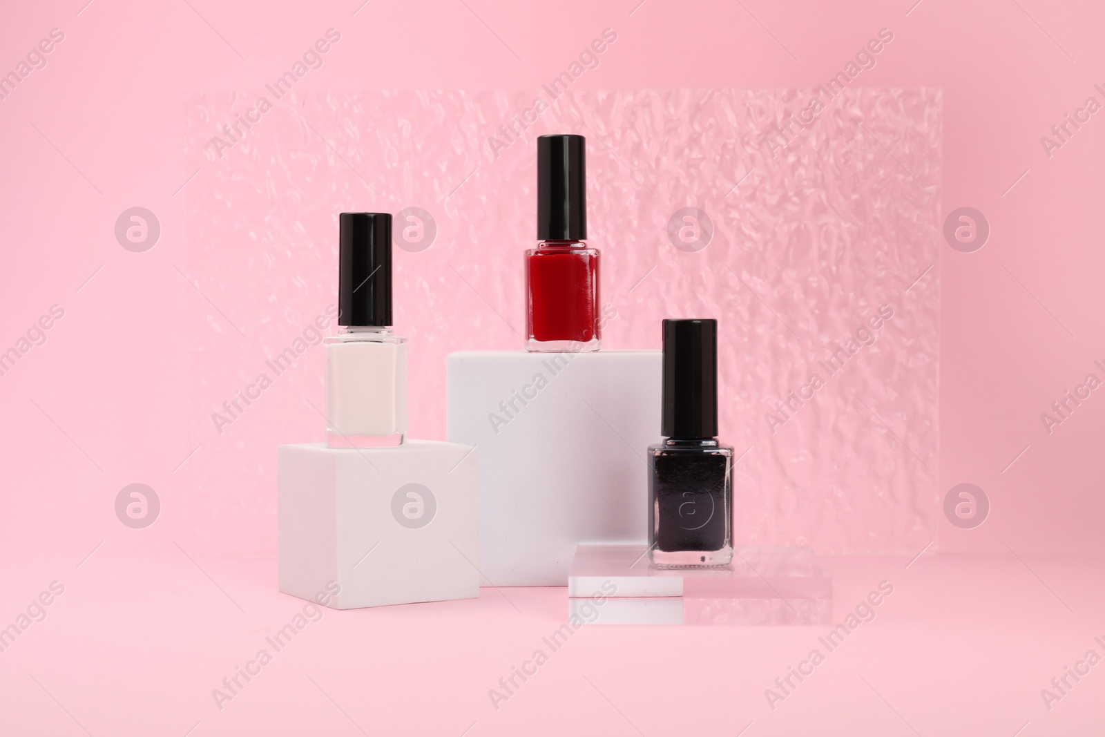 Photo of Stylish presentation of nail polishes on pink background