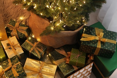 Photo of Many different gifts under Christmas tree indoors, above view