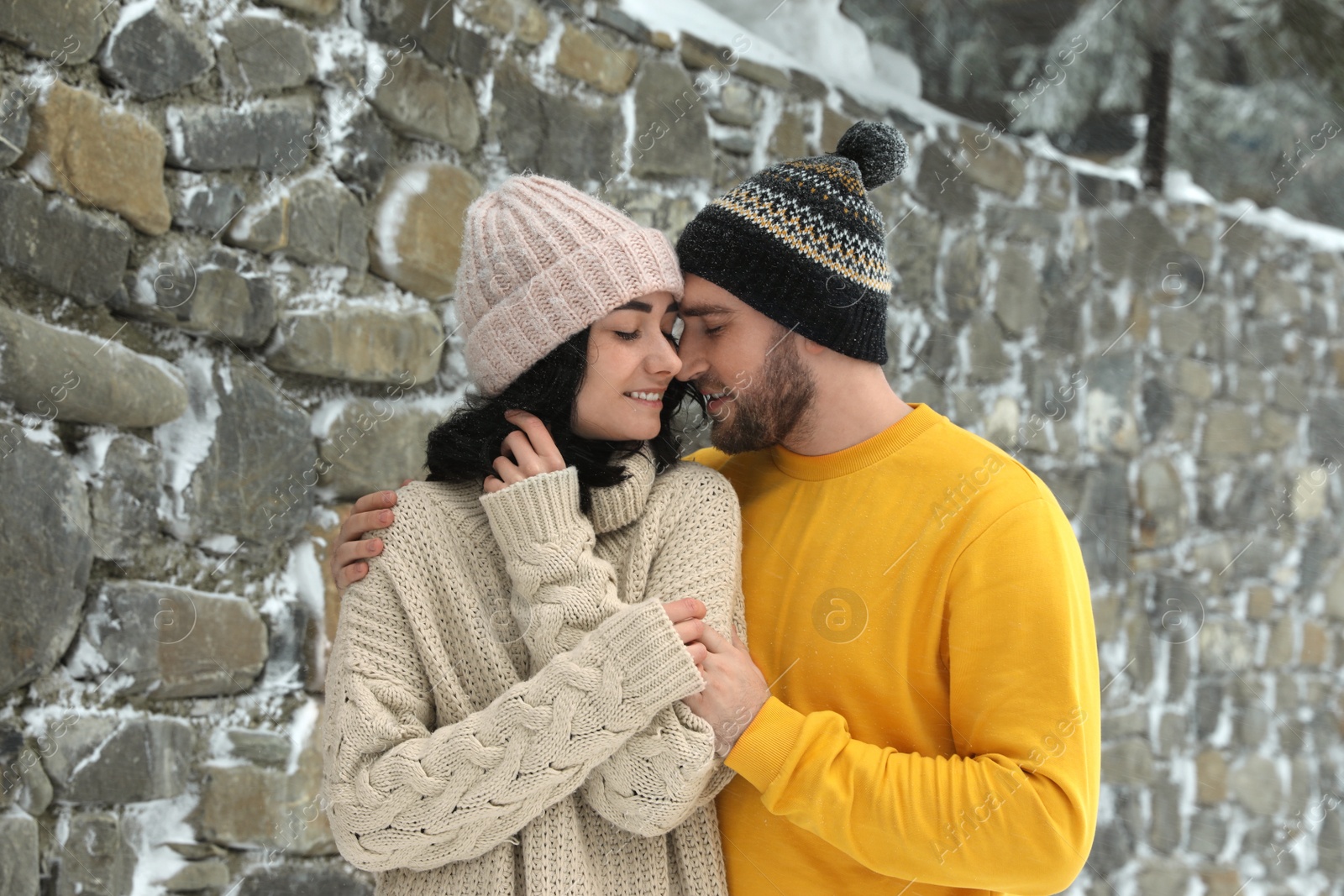 Photo of Lovely couple wearing warm sweaters and hats outdoors on snowy day. Winter season