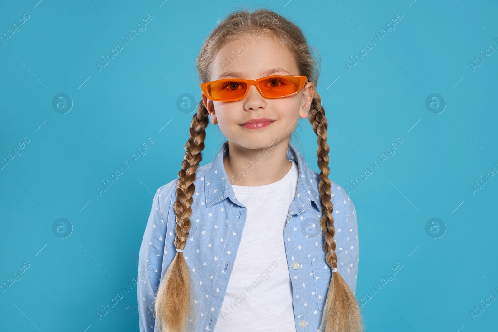 Photo of Girl in orange sunglasses on light blue background