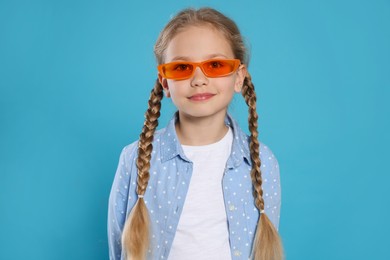 Girl in orange sunglasses on light blue background