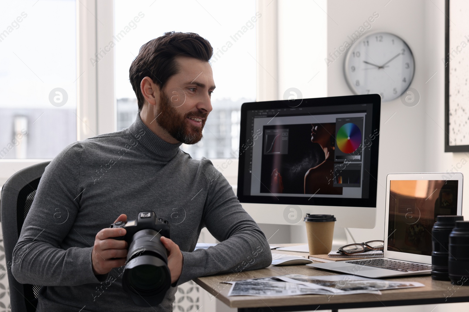 Photo of Professional photographer with digital camera at table in office