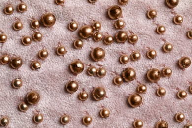 Beautiful pink fabric with golden beads as background, top view