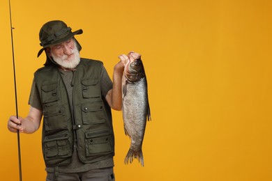 Photo of Fisherman with rod and catch on yellow background, space for text
