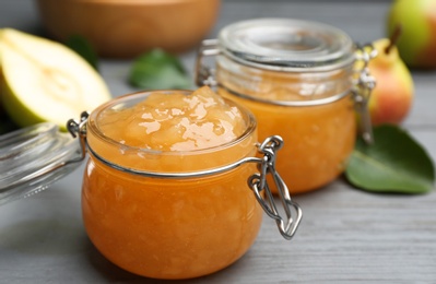 Photo of Delicious pear jam on grey wooden table, closeup