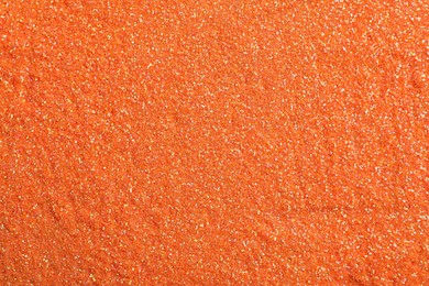 Photo of Shiny orange glitter as background, top view