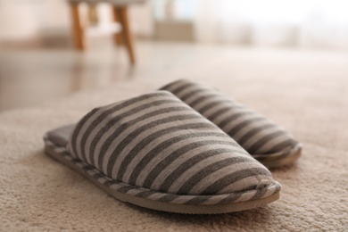 Photo of Pair of striped warm slippers on floor in room, closeup