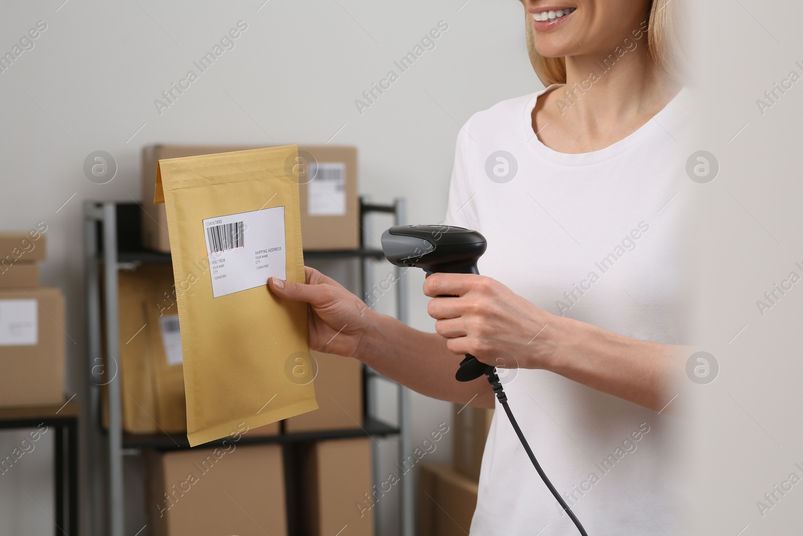 Photo of Seller with scanner reading parcel barcode in office, closeup. Online store