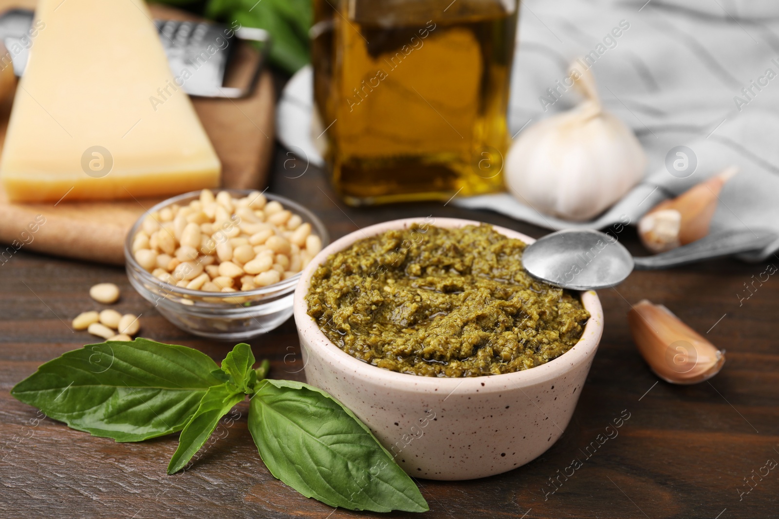 Photo of Tasty pesto sauce and ingredients on wooden table, closeup