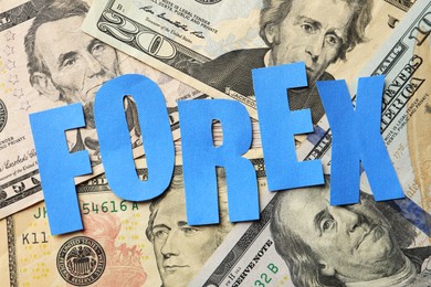 Photo of Word Forex made of blue letters on dollar banknotes, flat lay