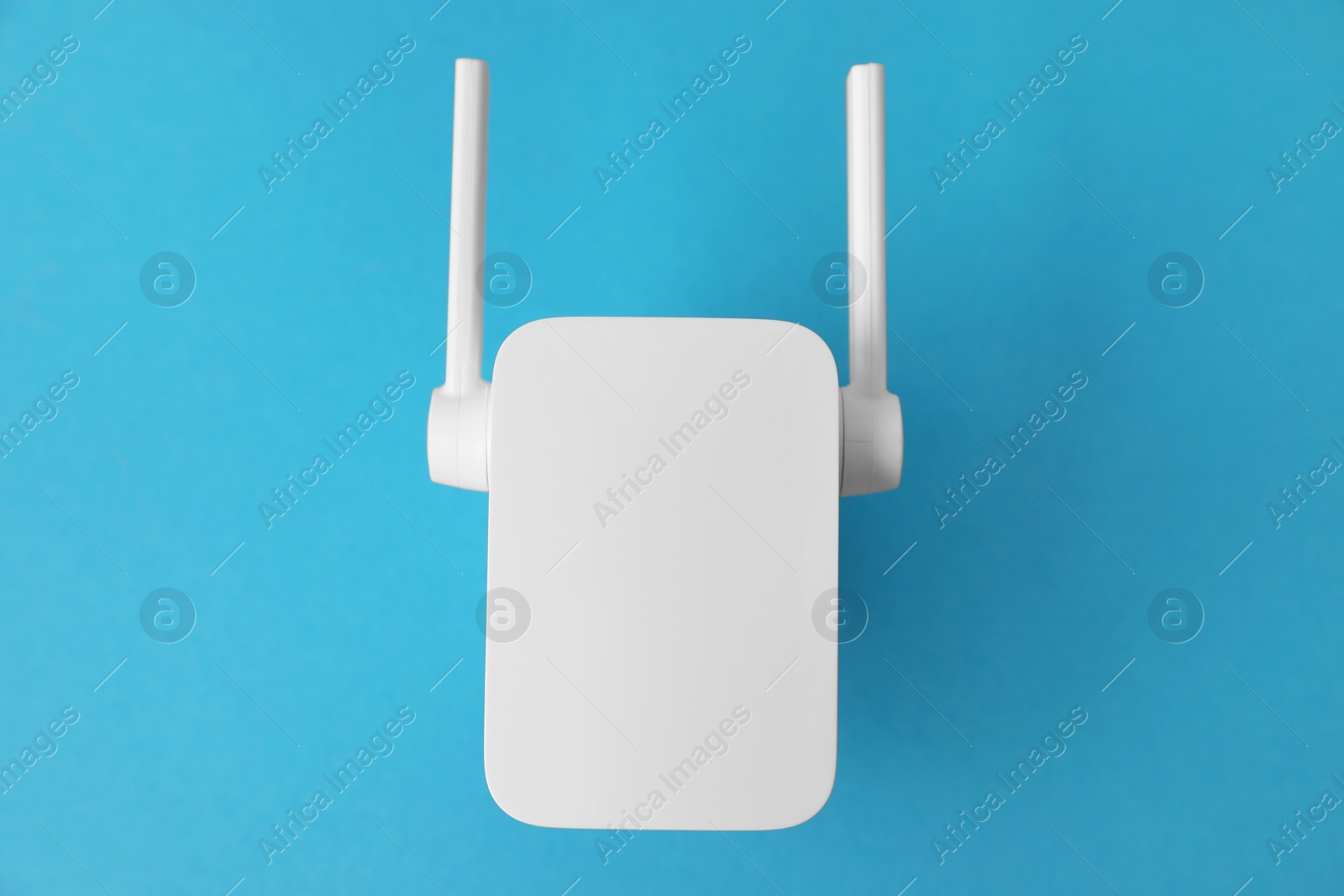 Photo of New modern Wi-Fi repeater on blue background, top view