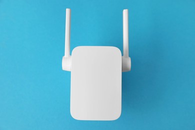 Photo of New modern Wi-Fi repeater on blue background, top view
