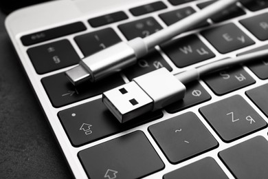 Photo of USB cable with type C connector and laptop on dark table, closeup