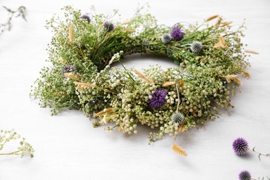 Beautiful wreath made of wildflowers on white table