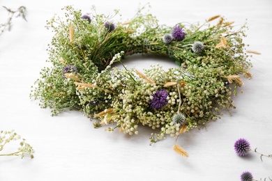 Photo of Beautiful wreath made of wildflowers on white table