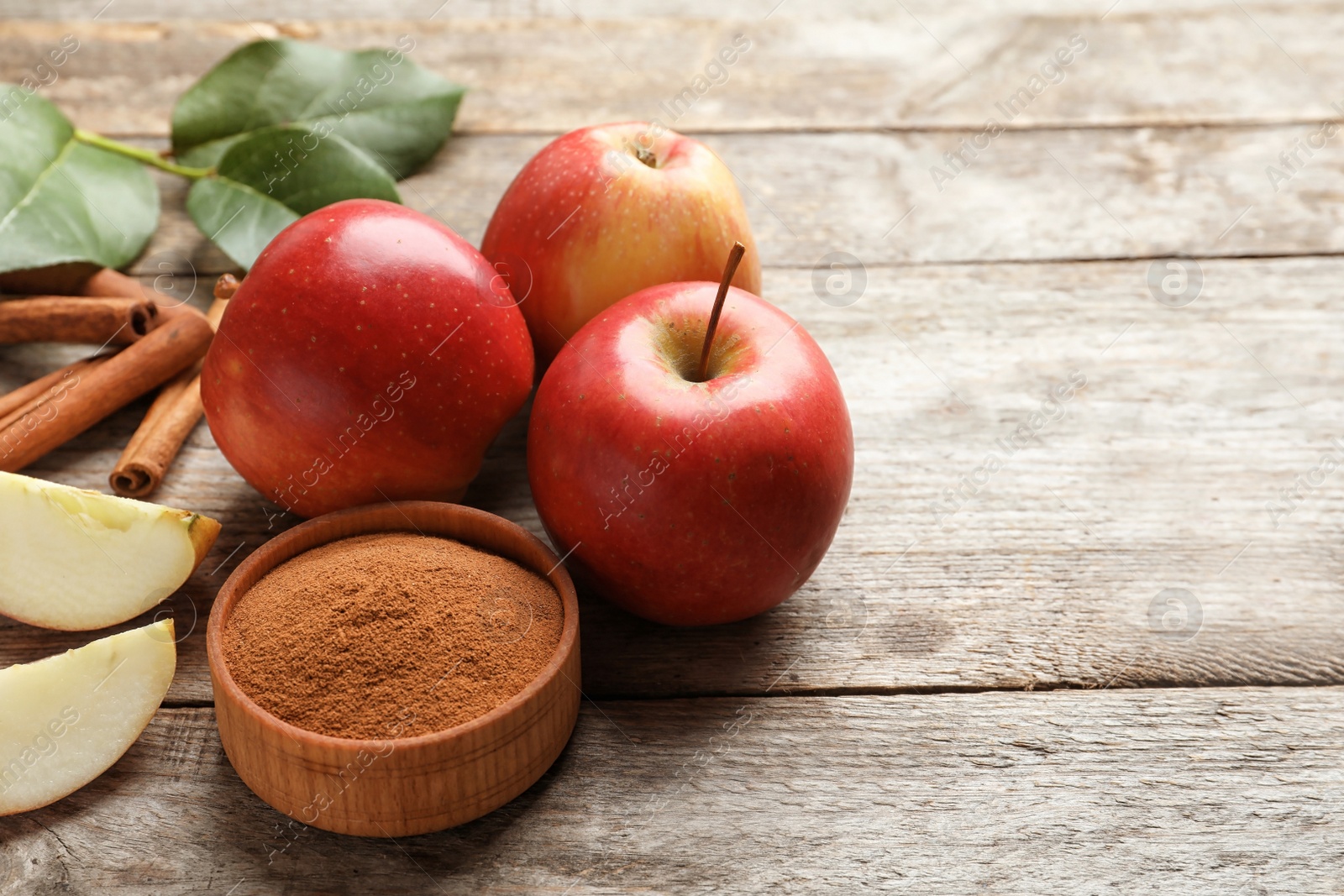 Photo of Fresh apples with cinnamon sticks and powder on wooden table