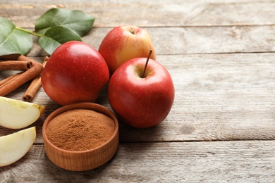 Photo of Fresh apples with cinnamon sticks and powder on wooden table