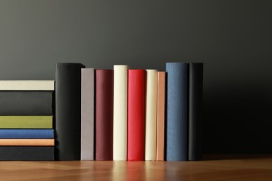 Photo of Many different books on wooden table near black wall, space for text