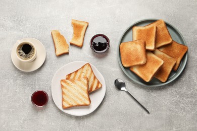 Photo of Slices of tasty toasted bread, jam and aromatic coffee on light grey table, flat lay