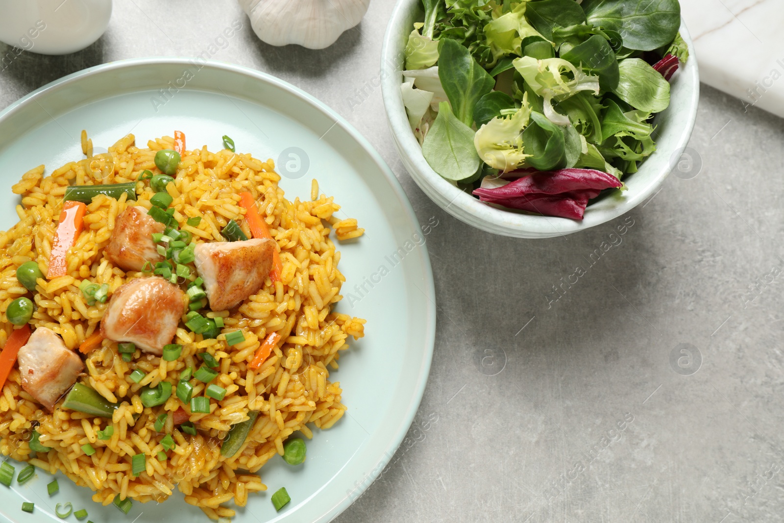 Photo of Delicious rice pilaf with vegetables and chicken served on light grey table, flat lay