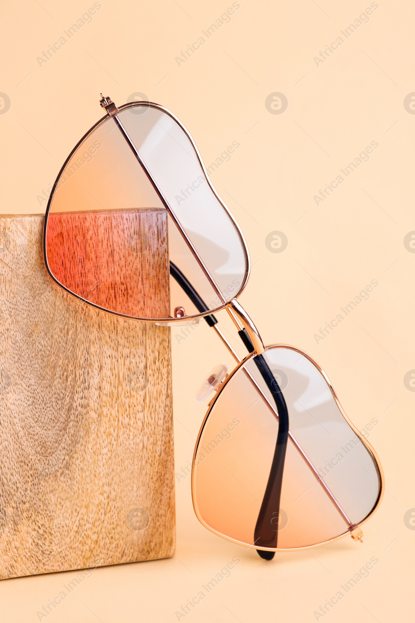 Photo of Stylish elegant heart shaped sunglasses on beige background