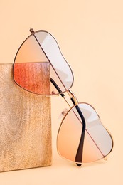 Photo of Stylish elegant heart shaped sunglasses on beige background