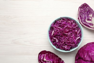 Photo of Tasty fresh shredded red cabbage in bowl on white wooden table, flat lay. Space for text