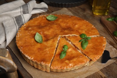Photo of Delicious pie with meat and basil on wooden table