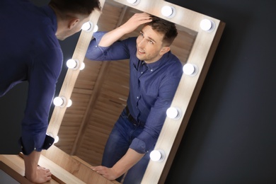 Photo of Young man looking at himself in mirror