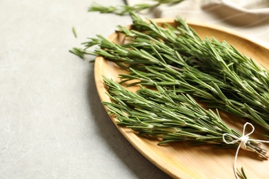 Photo of Wooden plate with fresh rosemary on table, closeup