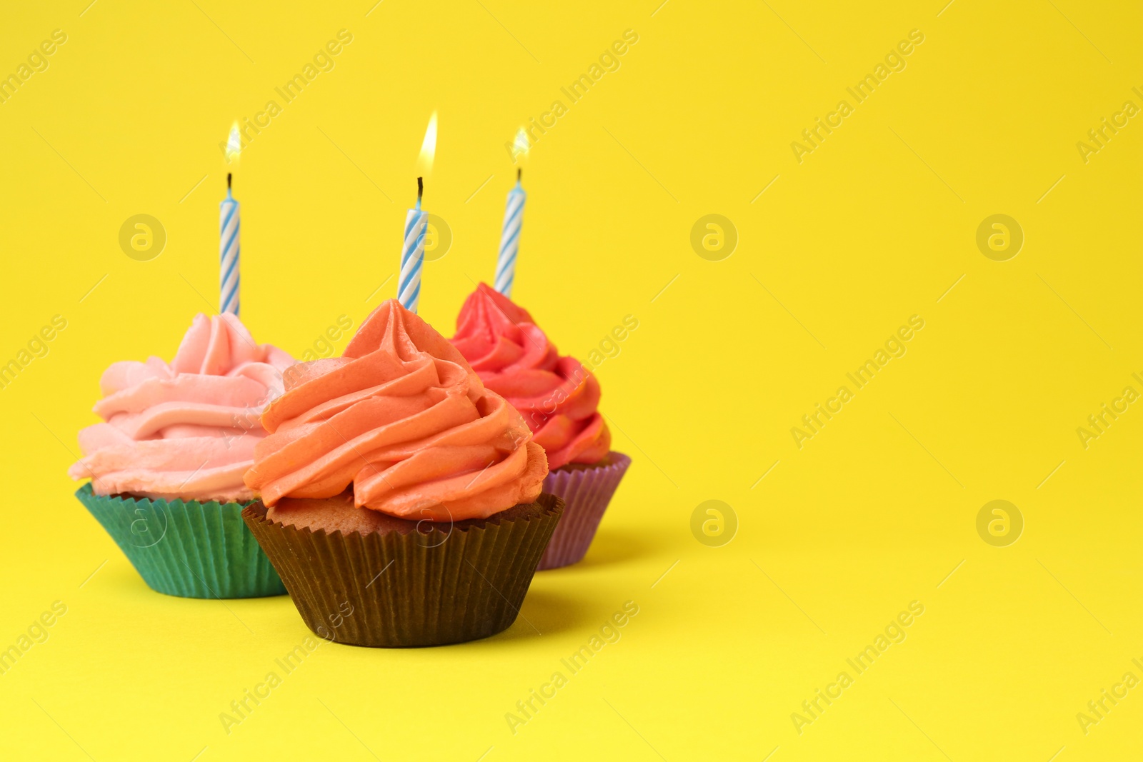 Photo of Delicious birthday cupcakes with bright cream on yellow background. Space for text