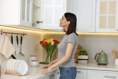 Beautiful young woman near kitchen cabinet at home