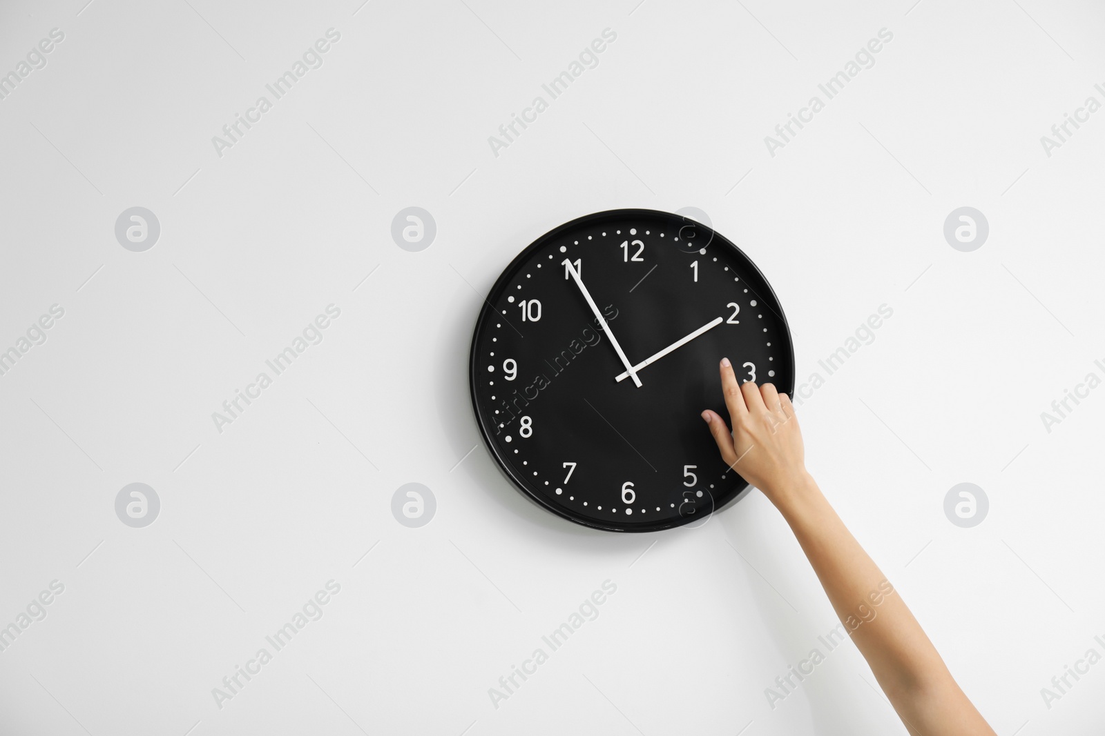 Photo of Woman pointing on clock against white background. Time concept