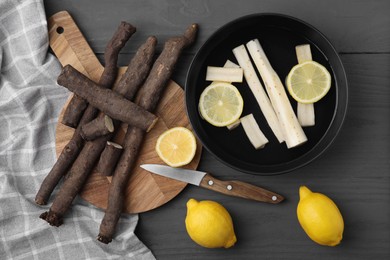 Photo of Raw salsify roots with lemon on grey wooden table, flat lay
