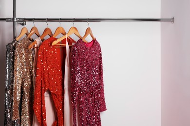Photo of Different shiny beautiful women's party dresses on hangers in showroom, space for text. Stylish trendy clothes for high school prom