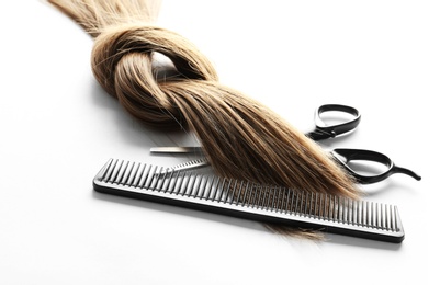 Photo of Beautiful brown hair, scissors and comb on white background. Hairdresser service