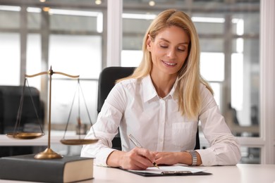 Photo of Smiling lawyer working at table in office