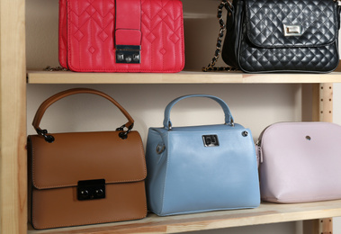 Photo of Collection of stylish leather bags on wooden shelving unit