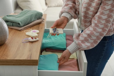 Photo of Woman putting scented sachet into drawer with clothes, closeup